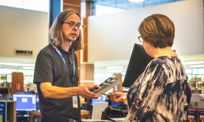 one person handing another person a library card